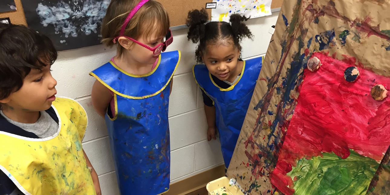 Three PIC preschoolers admiring art on an easel