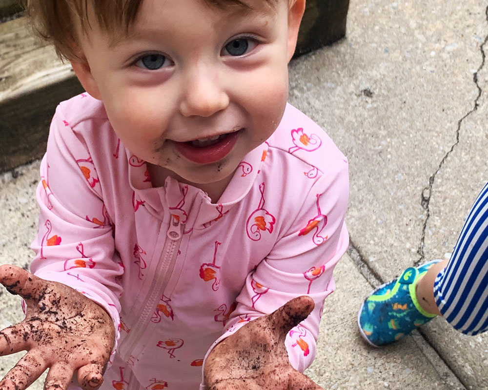 Mud Day 2025 - Young toddler showing muddy hands.