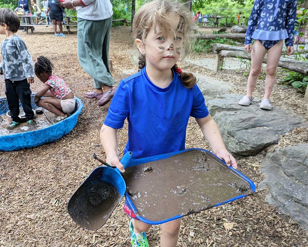 Mud Day 2025 - Child with big muddy tray and scoop.