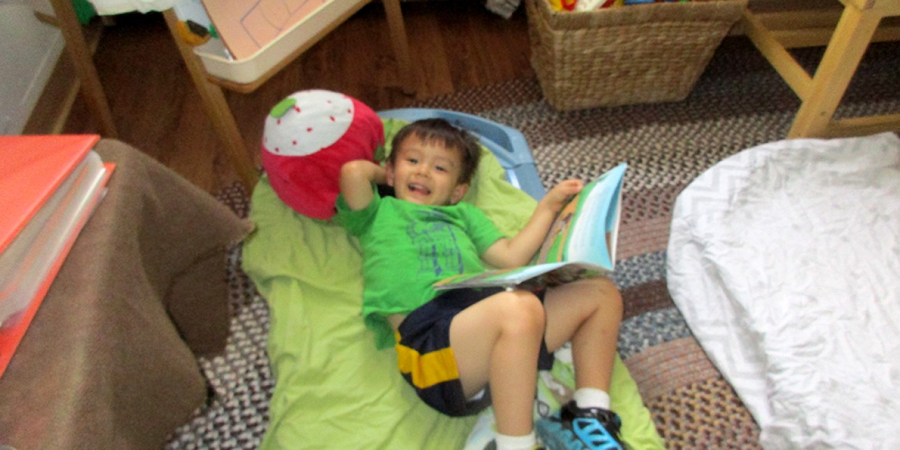 PIC preschooler rests with a book during nap time